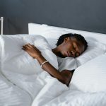 A man sleeping peacefully under a white blanket in a cozy bedroom.